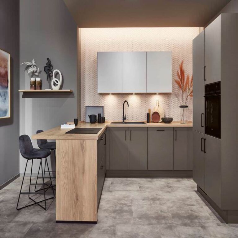 Exklusive U-Küche mit Holztresen – Küchenstudio Saarbrücken Exklusive U-Küche in Grau mit Tresen aus Holz, Barhockern und indirekter Beleuchtung