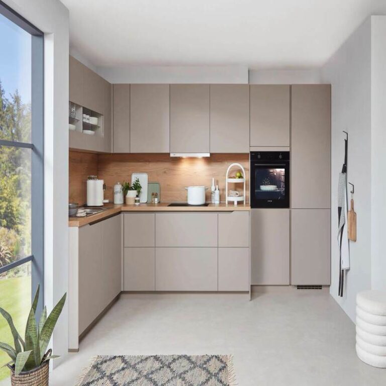 Musterküche in Kaschmir Musterküche in Kaschmir als L-Küche mit Holzrückwand und Backofen im Hochschrank – Küchenstudio Saarbrücken